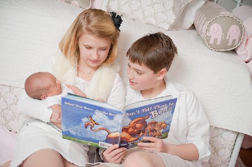Daniel and Caroline reading "Don't Tell That to Beasley" to their new little sister, Harrison.