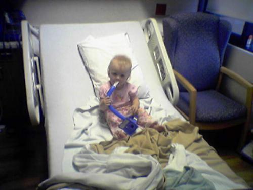 Alia in Daddy's hospital bed, doing his breathing machine.