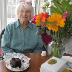Eva with a rich chocolate cake and flowers.