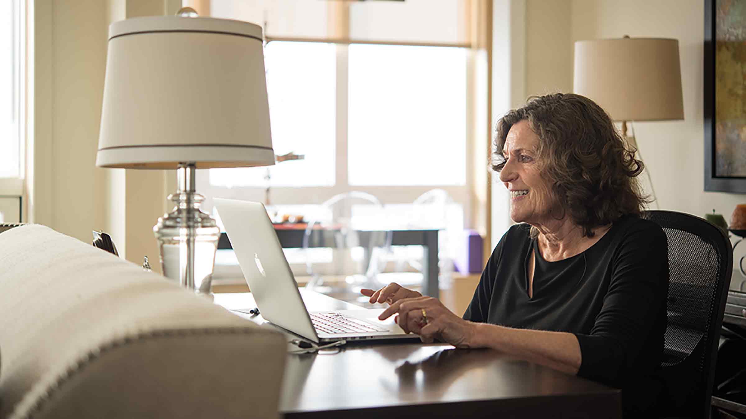 woman smiling and typing on laptop.